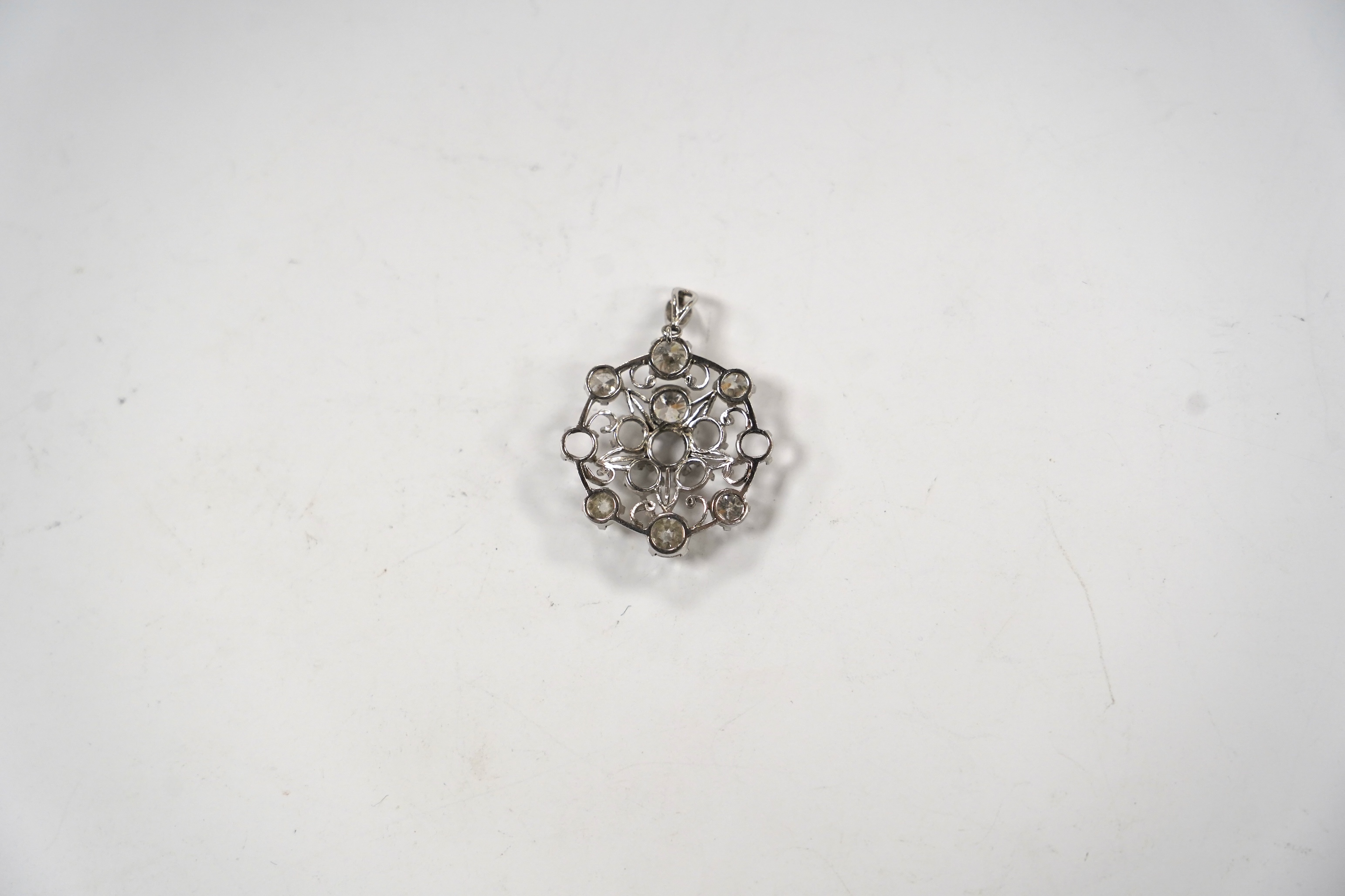 A white metal and diamond cluster set circular pendant (seven stones missing), largest stone diameter approx. 5.6mm, overall 35mm, gross weight 6 grams.